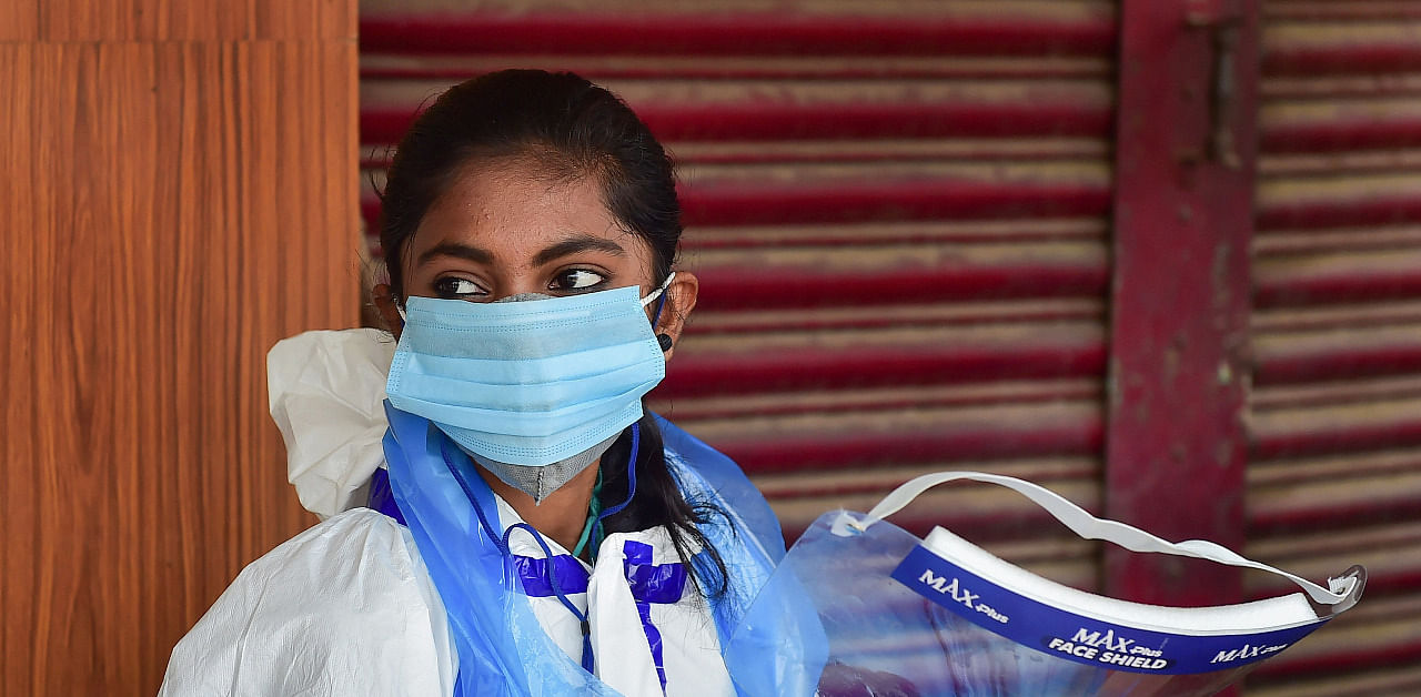 A medic waits for citizens willing to undergo Covid-19 tests at a road side free clinic, as coronavirus cases surge in Bengaluru. Credit: PTI Photo