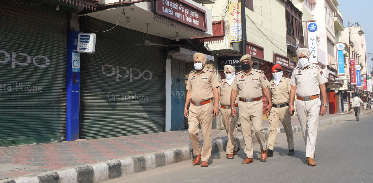 Punjab Police personnel walk near closed shops during Bharat Bandh, a nationwide farmers' strike, following the recent passing of agriculture bills in the Lok Sabha. Credit: AFP Photo