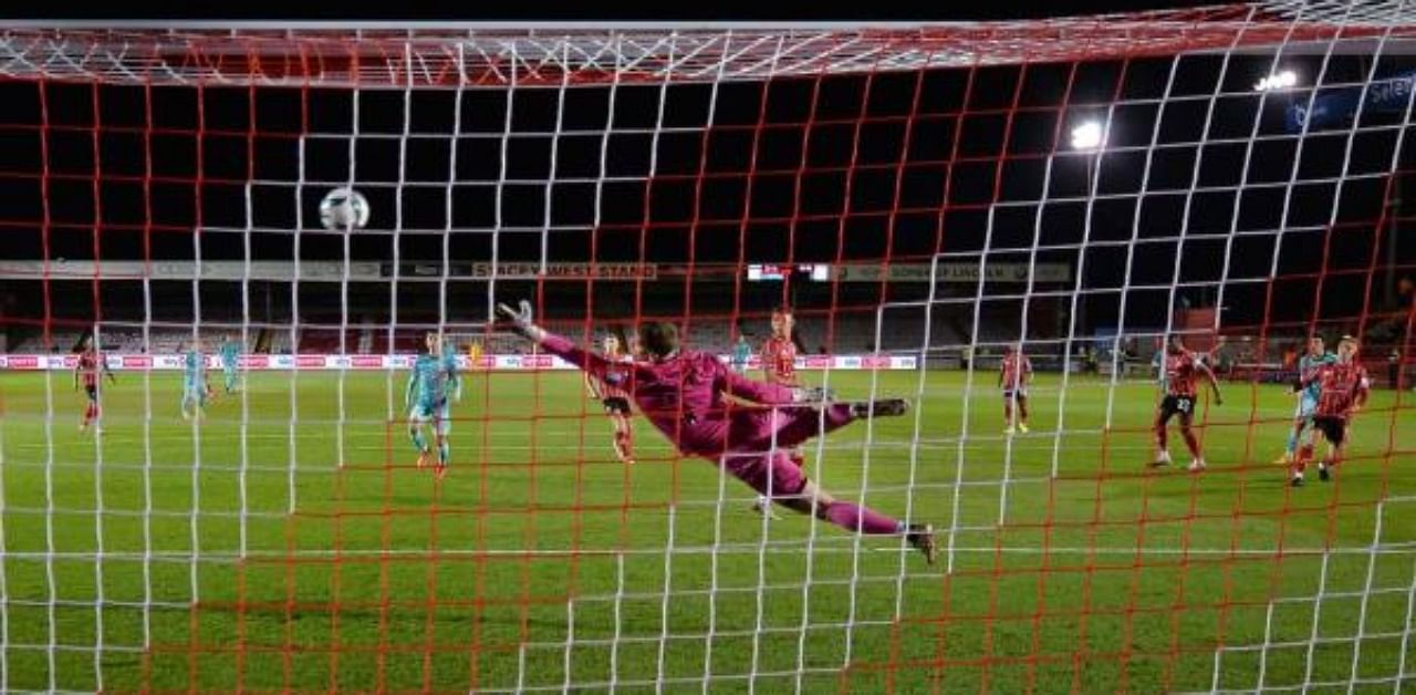 The ball goes past Lincoln City's English goalkeeper Alex Palmer (C) as Liverpool's English midfielder Curtis Jones (2nd R) scores his team's third goal during the English League Cup. Credit: AFP Photo