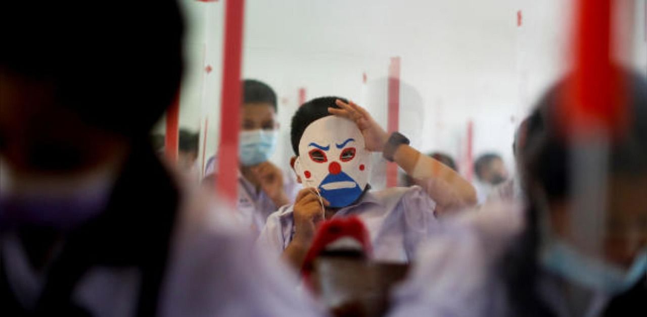 A boy displays a mask in a classroom of a school in Bangkok, Thailand. Credit: Reuters Photo