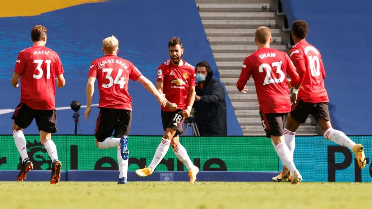 Manchester United's Portuguese midfielder Bruno Fernandes (C) celebrates with teammates after he takes a penalty and scores his team's third goal during the English Premier League football match between Brighton and Hove Albion and Manchester United. Credit: AFP.