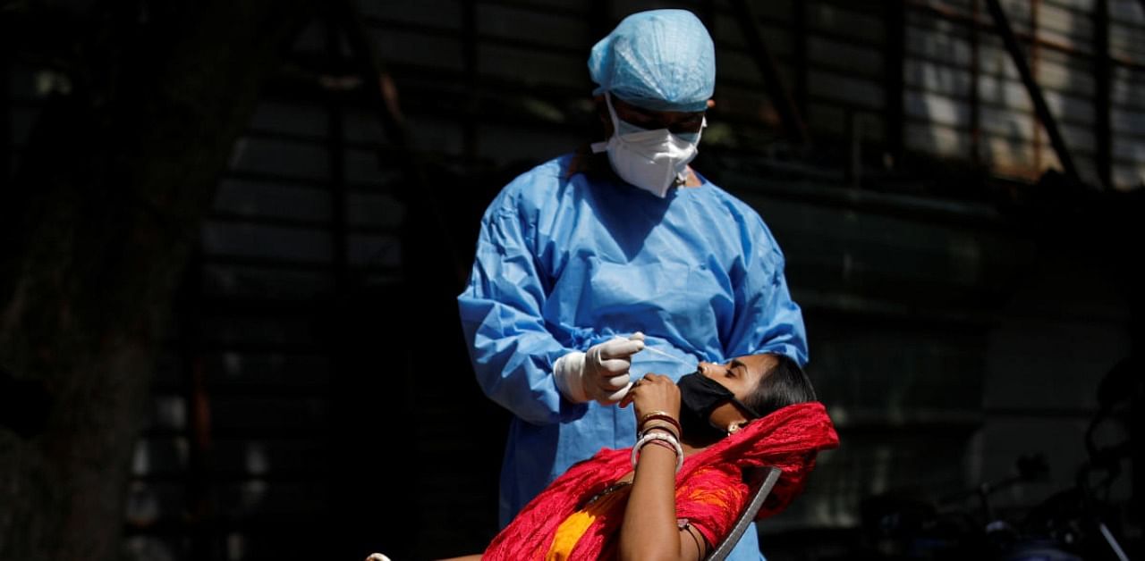 A healthcare worker wearing personal protective equipment (PPE) takes a swab from a migrant laborer for a rapid antigen test at the site of an under construction residential complex. Credit: Reuters