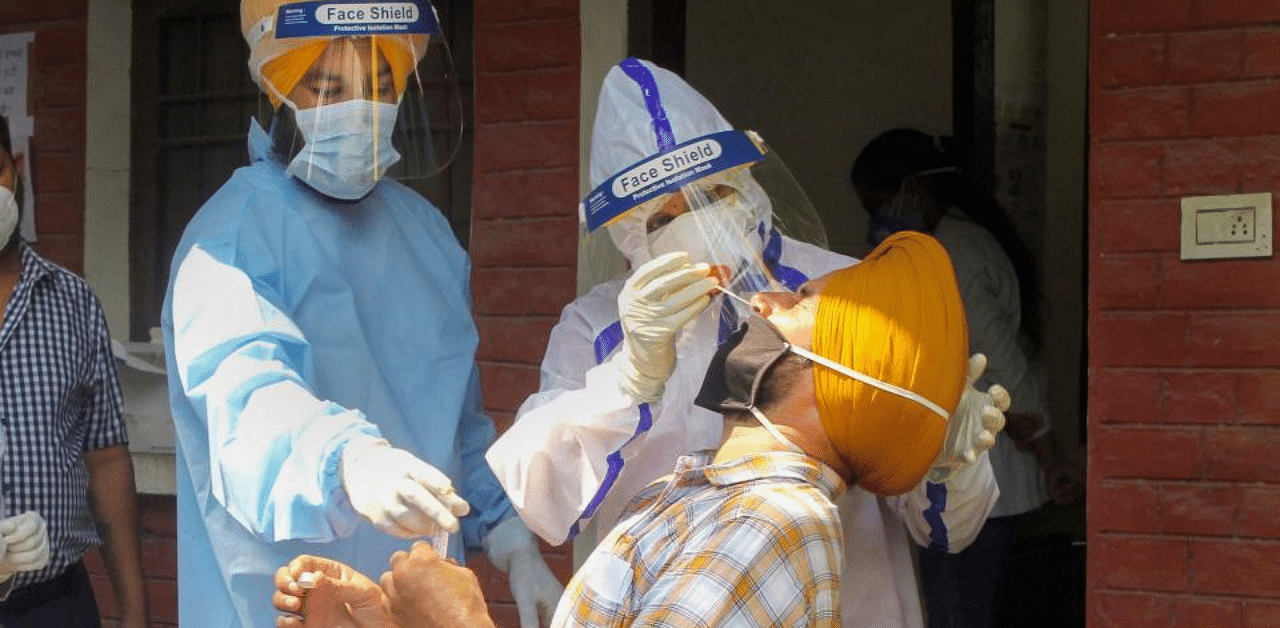 Health workers wearing PPE kits collect swab samples for Covid-19 testing, at a government dispensary in Patiala. Credit: PTI Photo
