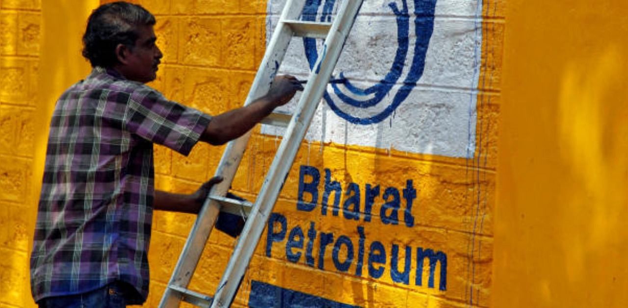 A man paints the logo of oil refiner Bharat Petroleum Corp (BPCL) on a wall. Credit: Reuters Photo