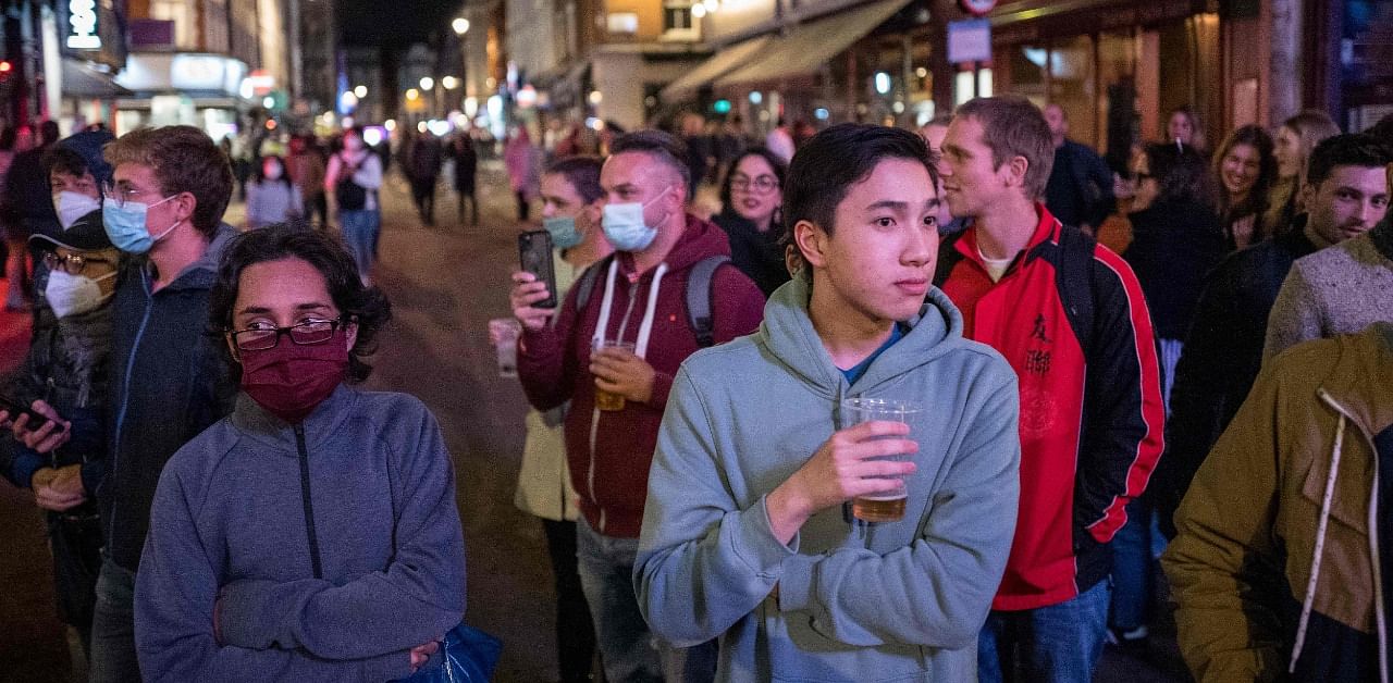 People finish their drinks in the street while the bars are being emptied in Soho, in central London. Credit: AFP Photo