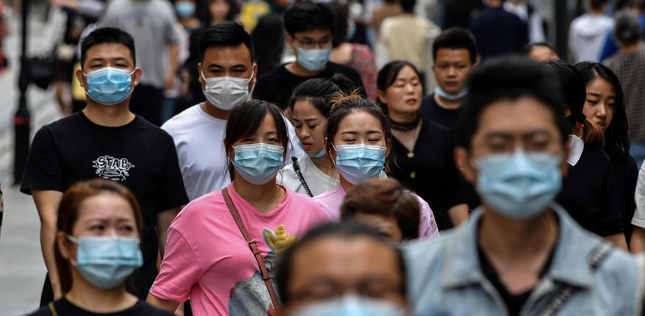 People wearing face masks as a preventive measure against the coronavirus walk on a pedestrian street in Wuhan. Credit: AFP Photo