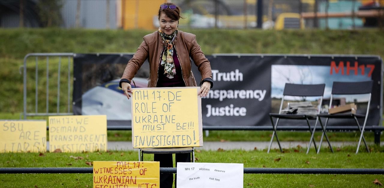 A pro-Russian protester holds a placard outside the high-security courtroom of the Schiphol Judicial Complex, in Badhoevedorp, where the lawsuit about the downing of flight MH17 continues. Credit: Reuters Photo