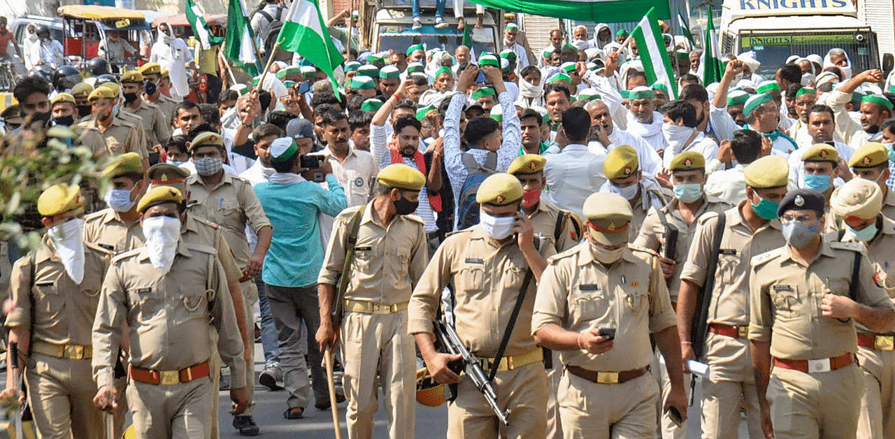 Police personnel keep a watch as farmers stage a protest march over various farmers' issues including new farm laws. Credits: PTI Photo