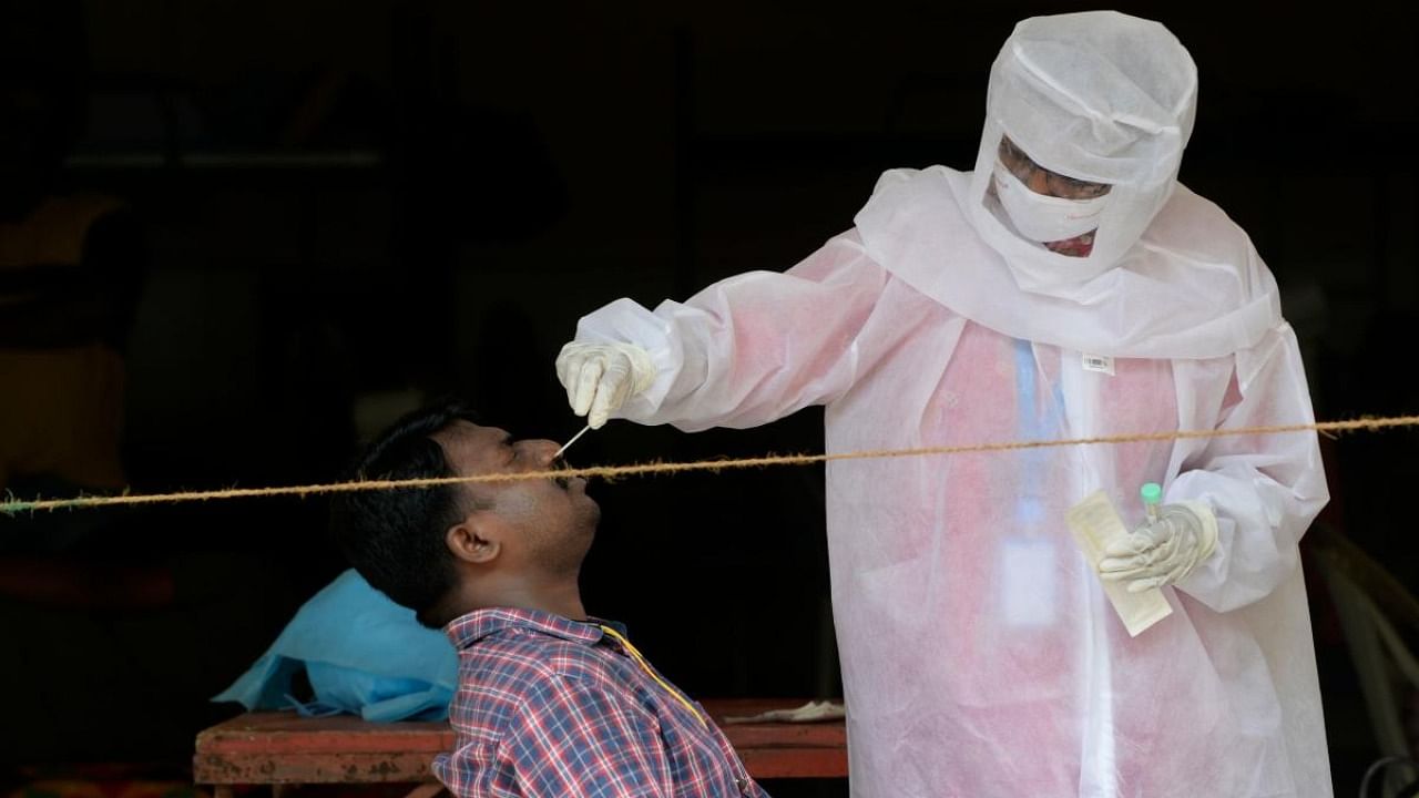 A health worker collects a nasal swab sample from a man to test for the coronavirus, in Mumbai. Credit: AFP