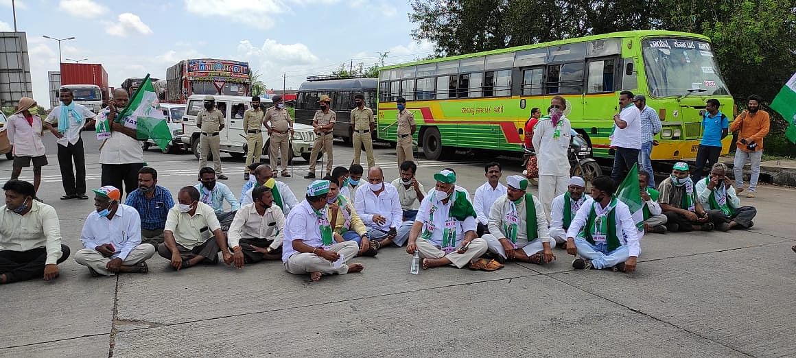 Congress-Janata Dal (Secular) workers staging sit-in protest by blocking the Pune-Bengaluru national highway near toll plaza at Hirebagewadi village in Belagavi taluk on Monday. Credit: DH Photo