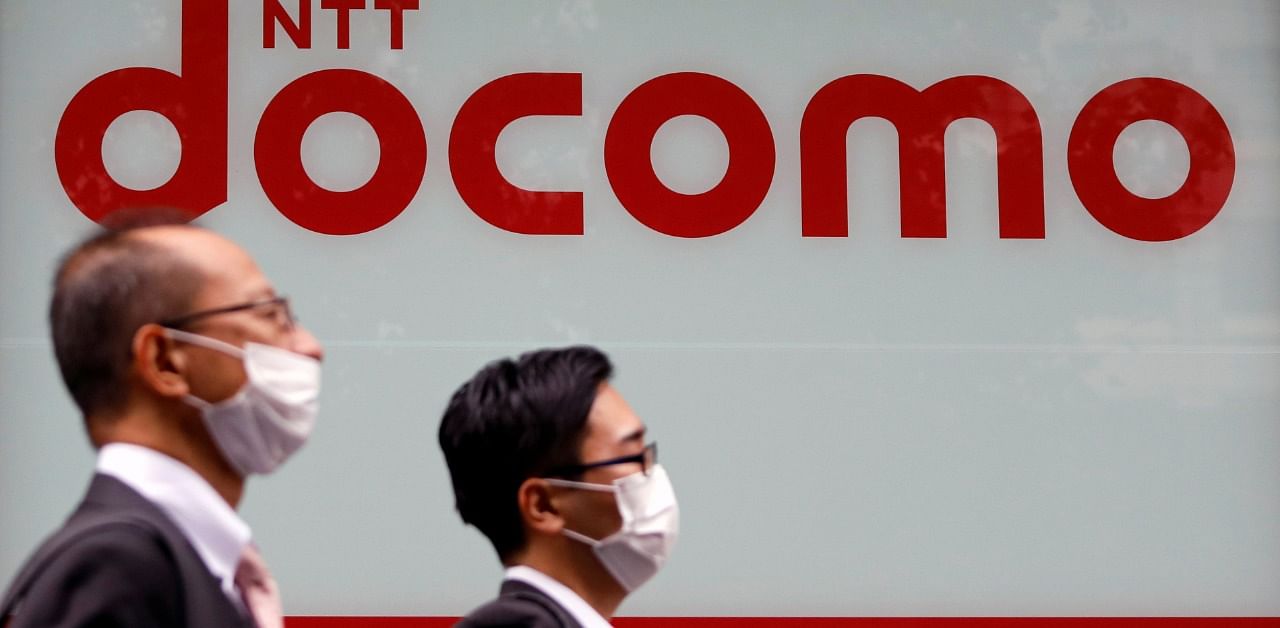 Passersby wearing protective face masks walk past in front of NTT Docomo shop in Tokyo, Japan. Credit: Reuters Photo