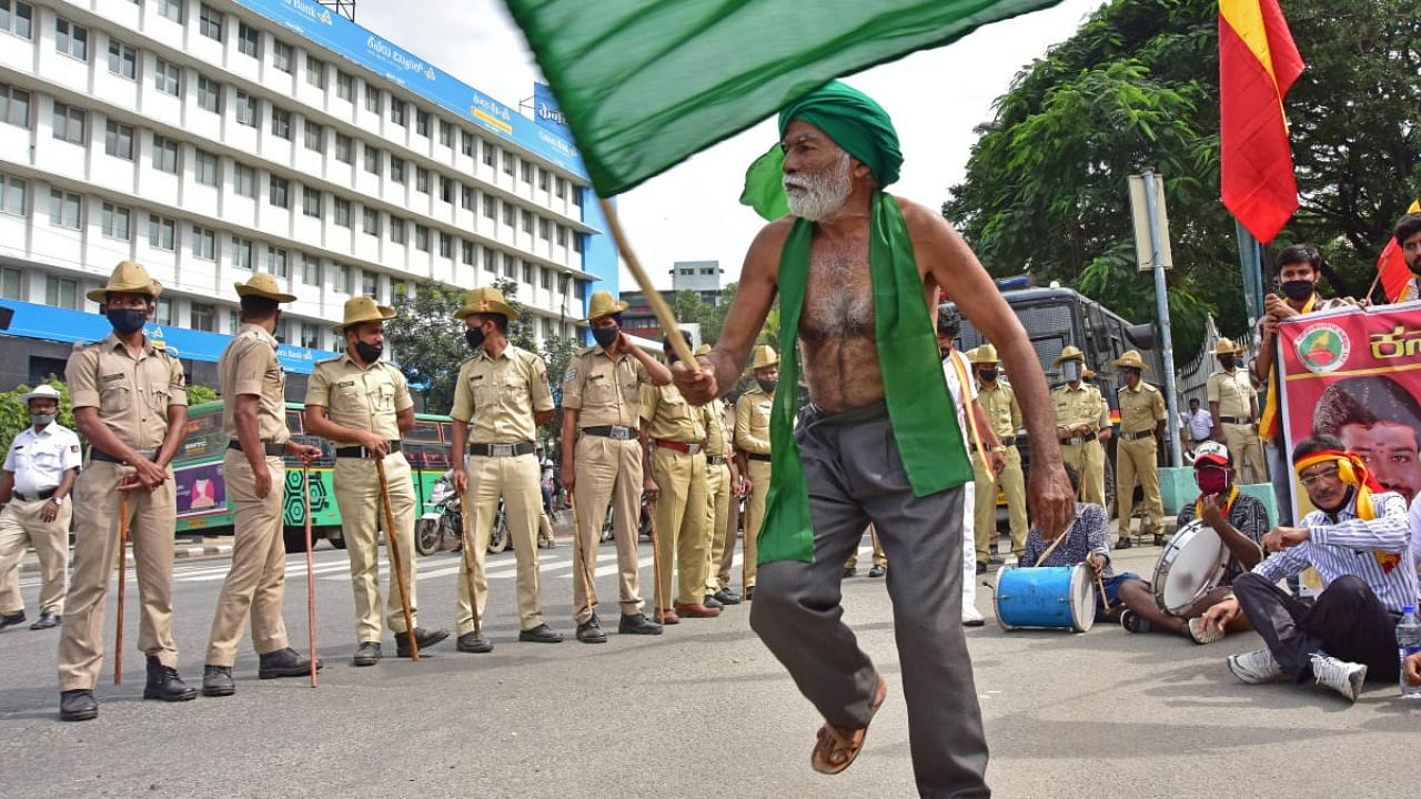 A protester waves a green flag associated with farmers during the protest at Town Hall in Bengaluru on Monday. DH PHOTO/Irshad Mahammad
