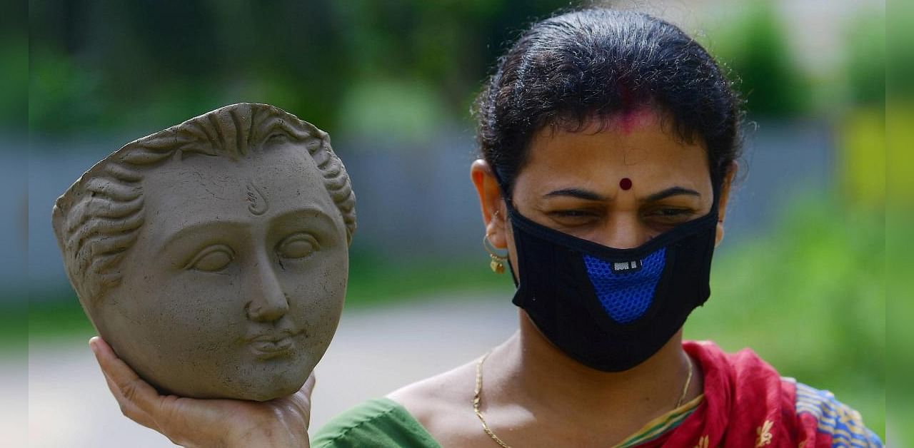 A woman artisan carries the face-idol of Goddess Durga at a studio, ahead of Durga Puja festival, in Agartala, Saturday, Sept. 26, 2020. Idol making business is badly hit this year due to coronavirus pandemic. Credit: PTI Photo