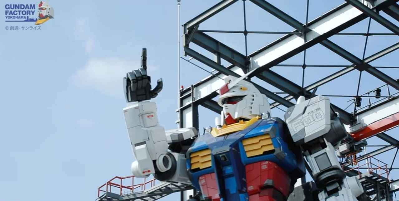 The 25-tonne Gundam makes a walking motion as it exits a storage area, before kneeling and then raising its right arm to point toward the sky. Credit: Twitter/@gundam_info
