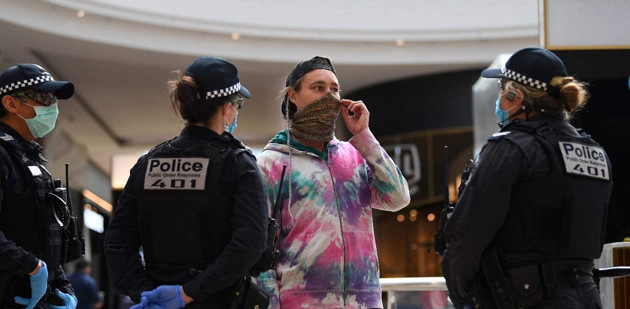 Victoria Police officers speak with a masked member of the public in a shopping centre. Credit: Reuters Photo