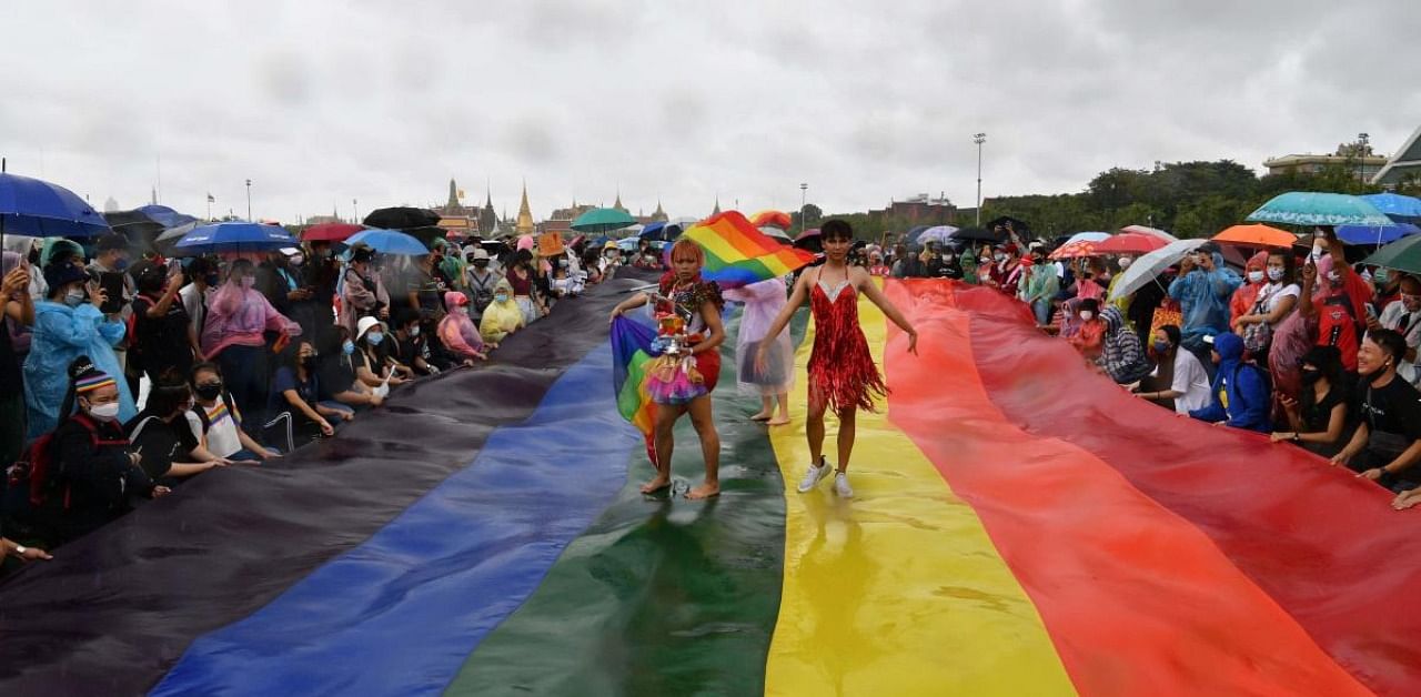 Activists walk on a large rainbow flag -- a symbol of the lesbian, gay, bisexual, transgender community -- during an anti-government rally at Thammasat University in Bangkok. Credit: AFP