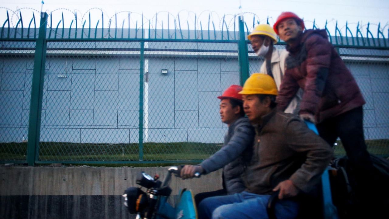 Workers ride past the perimeter fence of what is officially known as a vocational skills education centre in Dabancheng, in Xinjiang Uighur Autonomous Region. Credit: Reuters.