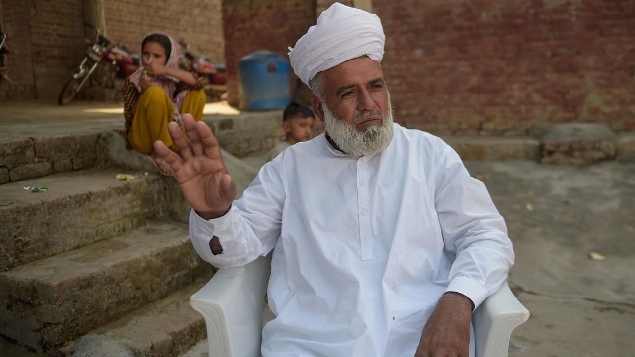 In this picture taken on September 29, 2020 Arshad Mehmood, father of Hassan Arshad (3R), an 18-year-old Pakistani born who injured two people in a meat cleaver attack in Paris, gestures while talking with media representatives at his home in Kothli Qazi village some 130 km from Islamabad. Credit: AFP.