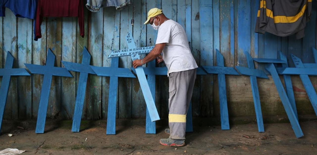 Brazilian Ulisses Xavier, 52, who has worked for 16 years at Nossa Senhora cemetery in Manaus, Brazil, places wooden crosses made by him on a wall at his house, amid the new coronavirus pandemic. Credit: AFP