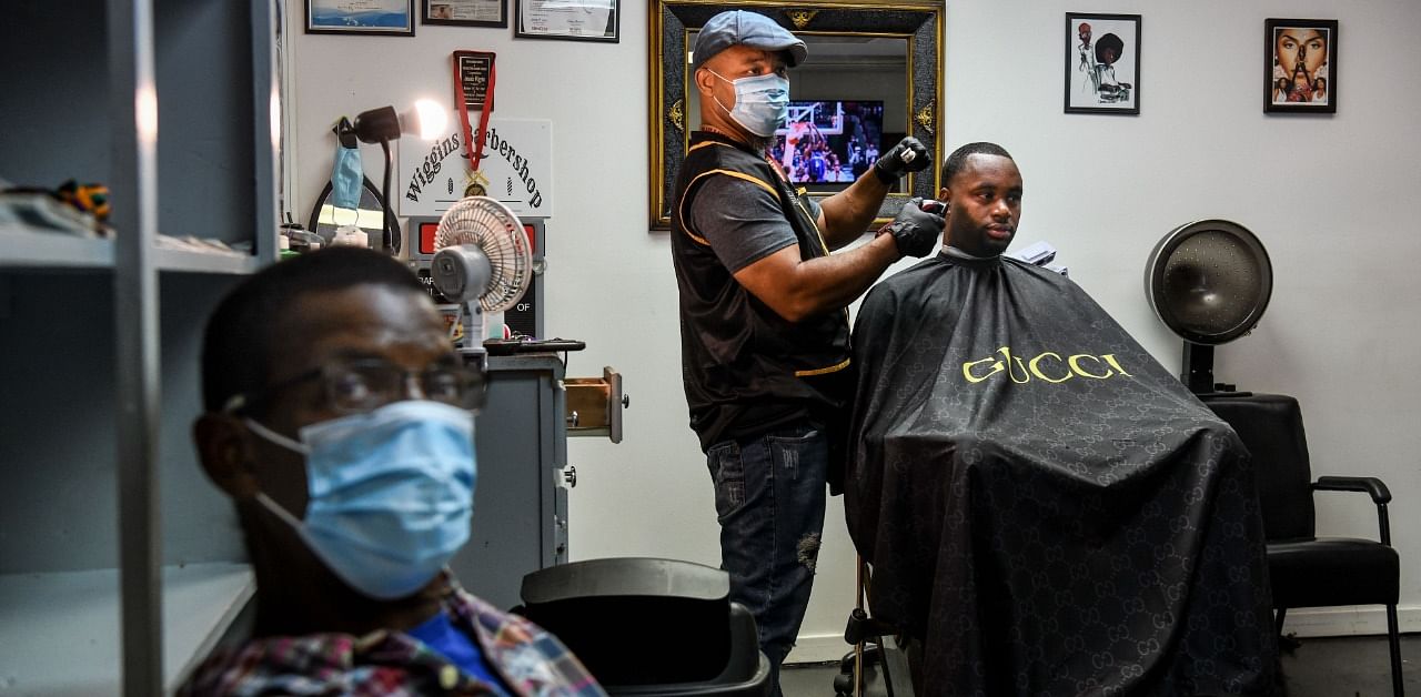 Antonio Wiggins (C) cuts the hair of James Bennett (R) as Robert White (L) waits for his turn, inside his barber shop in Jackson, Mississippi. Credit: AFP Photo