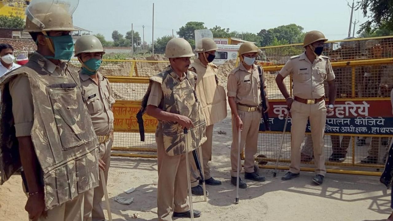 Police personnel stand guard at the entrance of Bulgadi village where the family of 19-year-old Dalit woman who was gang-raped two weeks ago resides, in Hathras. Credit: PTI.