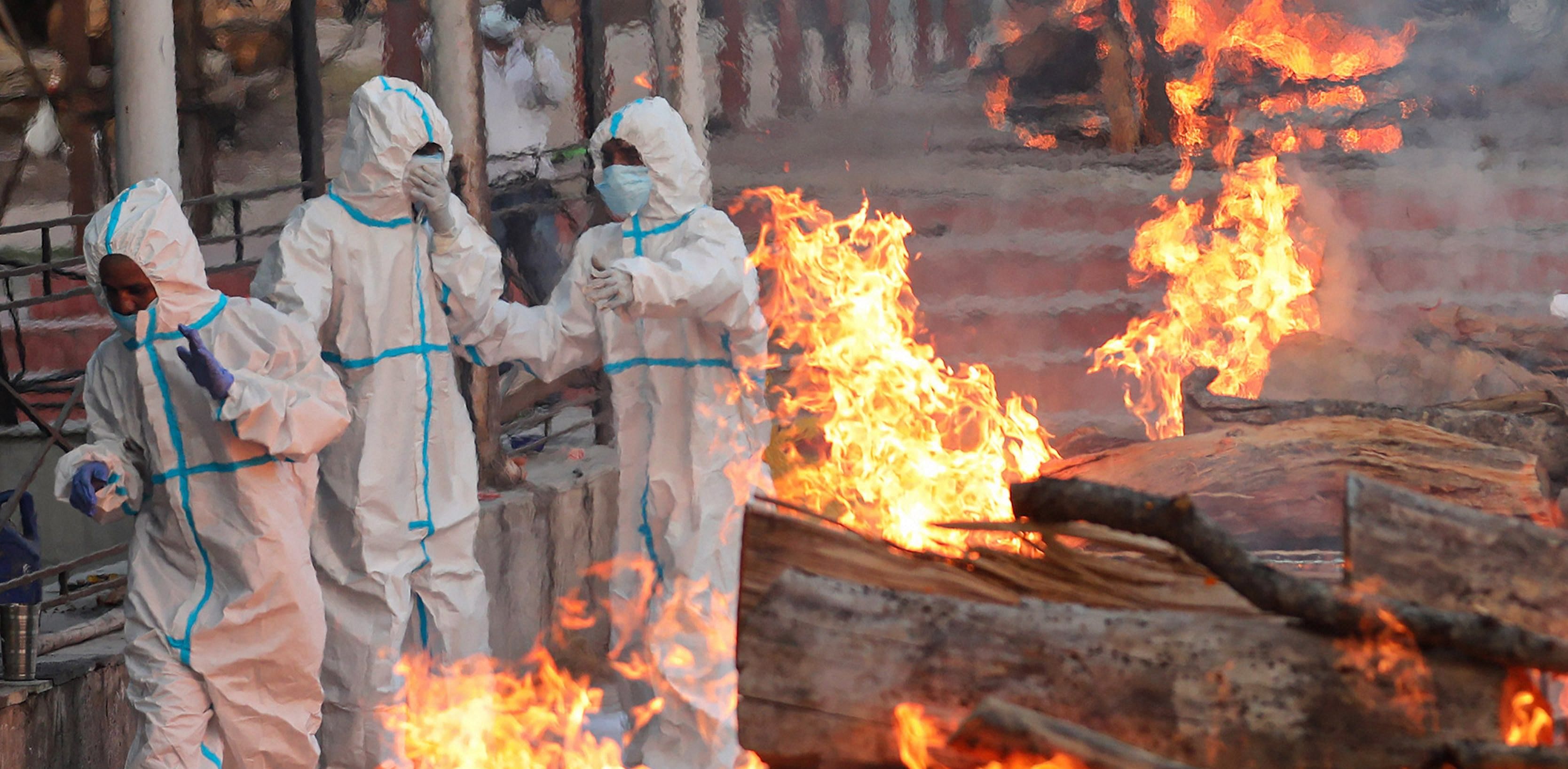 Relatives and health workers wearing protective suits cremate persons who died of COVID-19, in Jammu. Credit: PTI