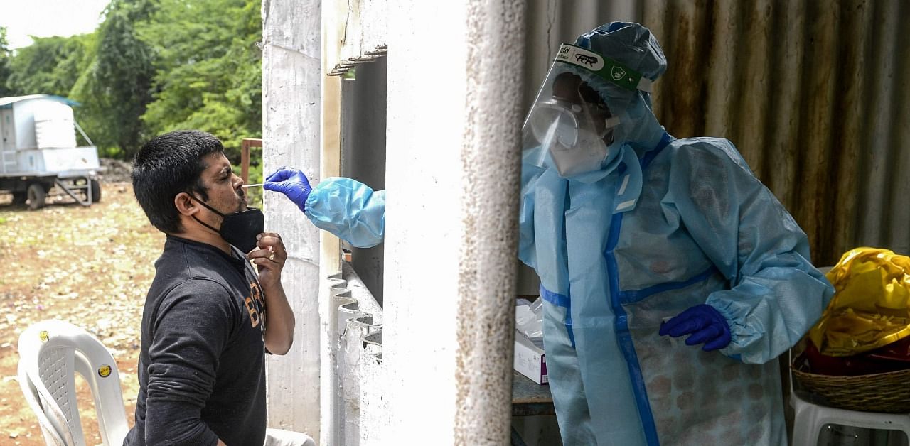 A health worker collects a swab sample from a resident for a Covid-19 test at a temporarory collection centre. Credit: AFP Photo