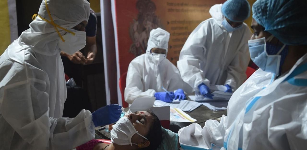  A health worker wearing protective gear collects a swab sample from a resident during a medical screening for the Covid-19 coronavirus at a police colony in Mumbai. Credit: AFP