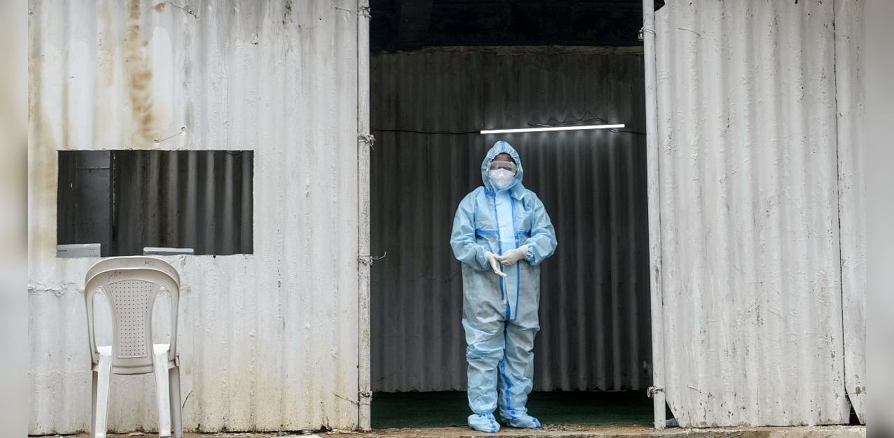 A health worker wearing personal protective equipment (PPE) waits to collect swab samples from residents for Covid-19 coronavirus tests at a temporarory collection centre in Secunderabad, the twin city of Hyderabad on October 1, 2020. Credit: AFP Photo