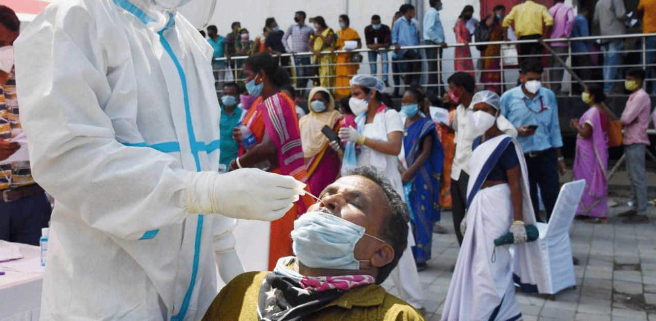 A health worker takes samples for Covid-19 Rapid Antigen Tests, as coronavirus cases surge across the city, in Guwahati. Credit: PTI Photo