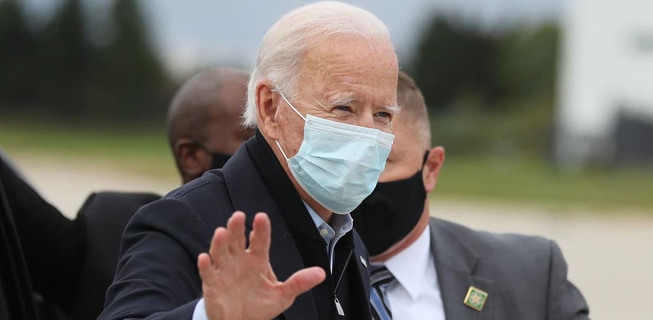 Wearing a mask to reduce the risk posed by the coronavirus, Democratic presidential nominee Joe Biden waves while preparing to board his plane. Credit: AFP