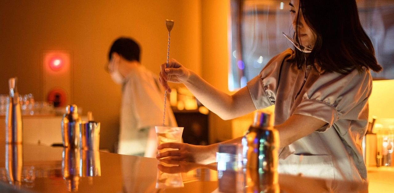 A bartender (R) making a cocktail in a non-alcoholic bar in Tokyo. - At a trendy Tokyo cocktail bar, customers sip on brightly coloured beverages with sophisticated flavour profiles, designed for a small but growing market in hard-drinking Japan: teetotallers. Credit: AFP Photo