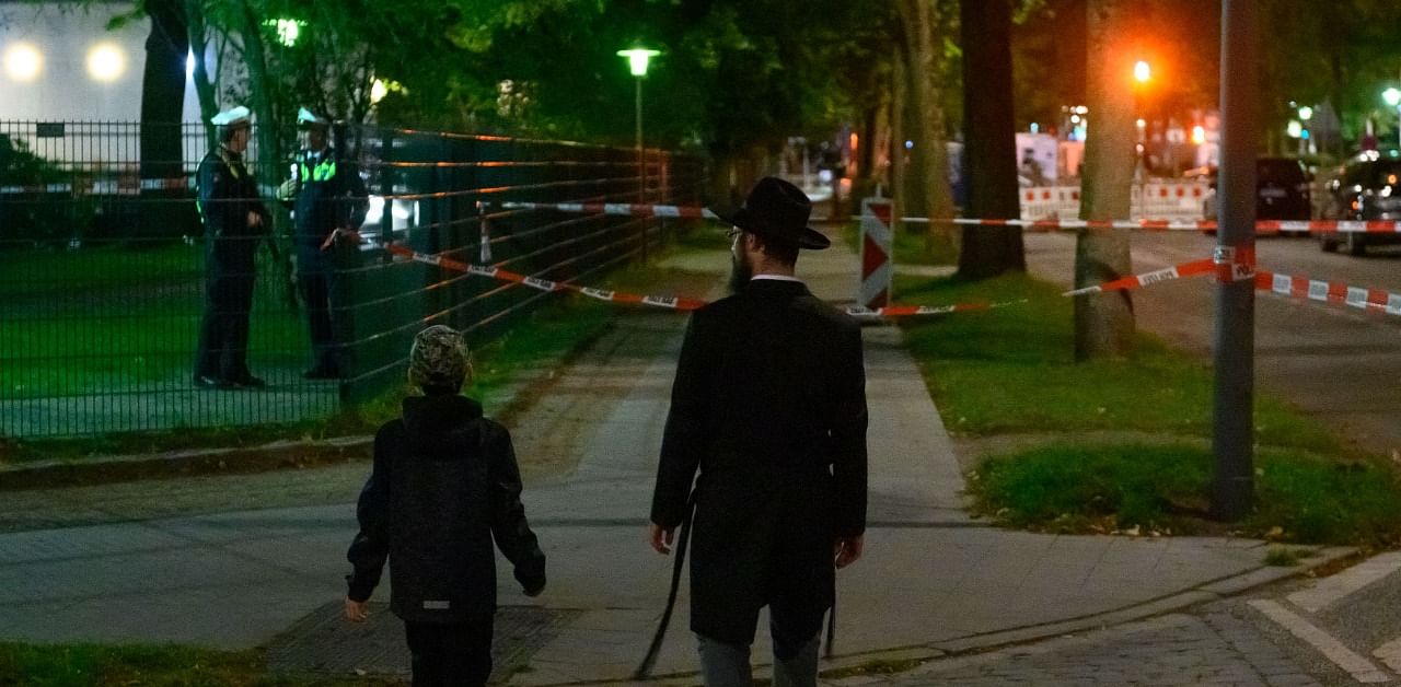 A man and a boy walk towards the police cordoned-off area in front the Hamburg' synagogue, where an apparent anti-Semitic attack happened in Hamburg, northern Germany. Credit: AFP Photo
