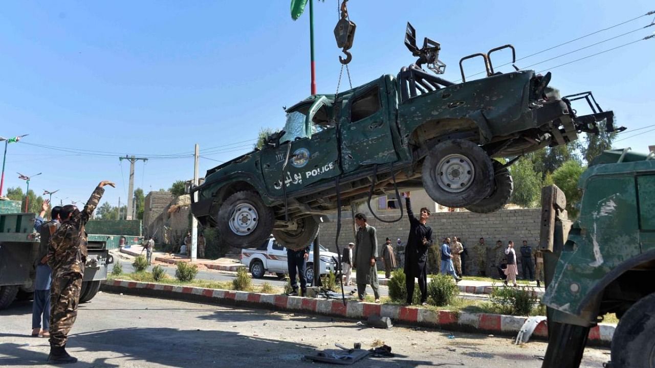Afghan security forces removes a damaged police vehicle at the site of a car bomb attack that targeted Laghman provincial governor's convoy, in Mihtarlam, Laghman Province. Credit: AFP.