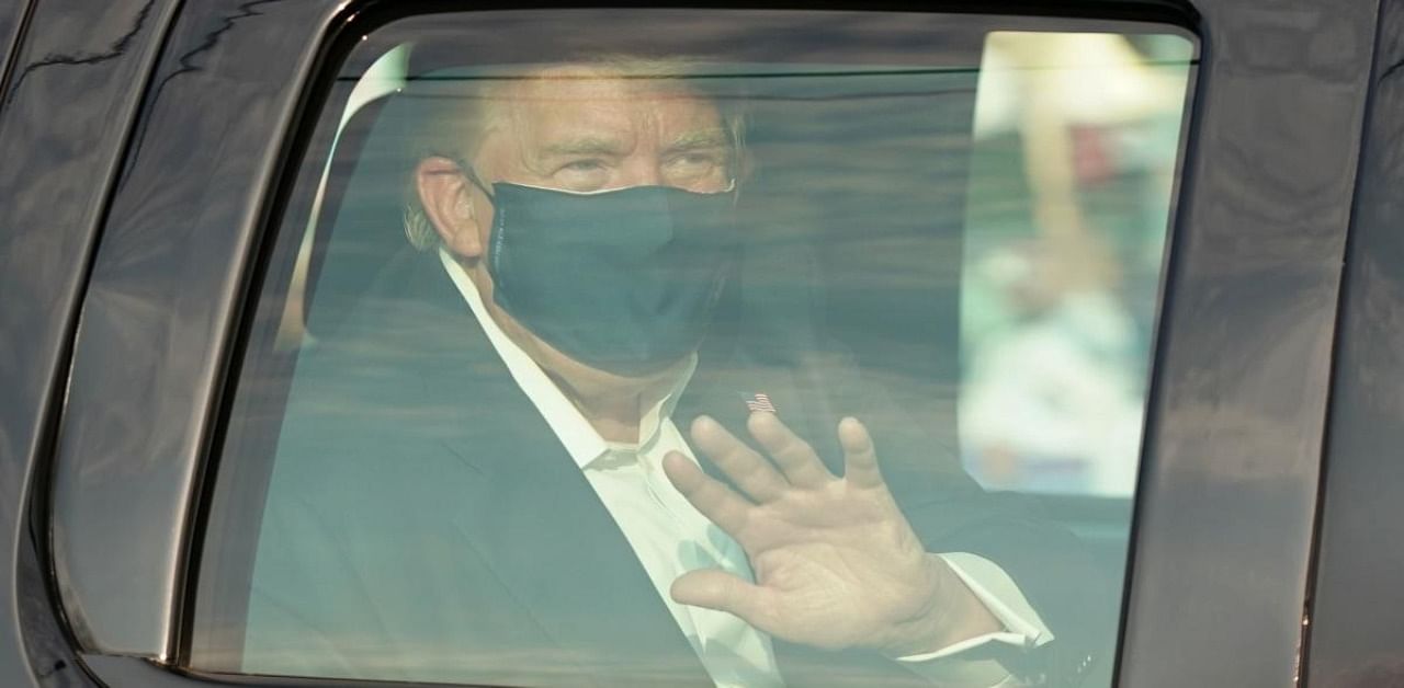 US President Trump waves from the back of a car in a motorcade outside of Walter Reed Medical Center. Credit: AFP