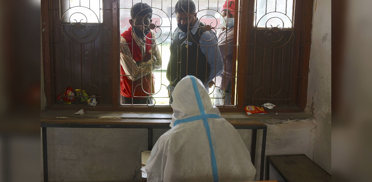 People wait for reports after giving their samples for COVID-19 Rapid Antigen test, during Unlock 5, in Srinagar. Credit: PTI