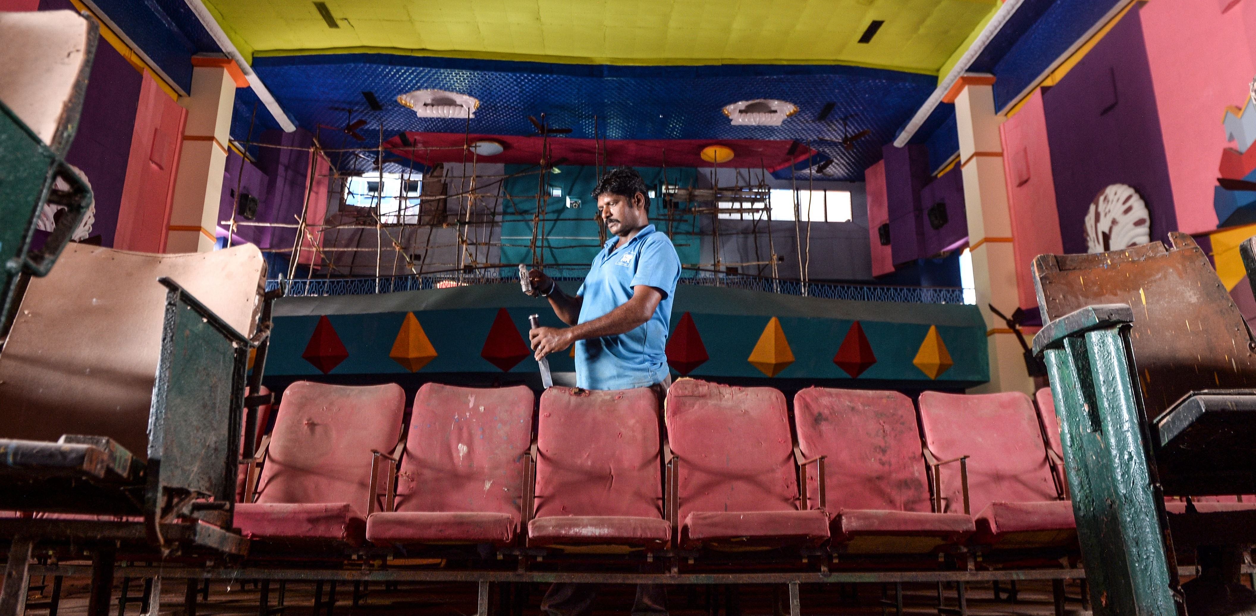 A worker does maintenance work at a cinema hall as part of preparations for a possible reopening after the government eased lockdown restrictions in Chennai. Credit: AFP