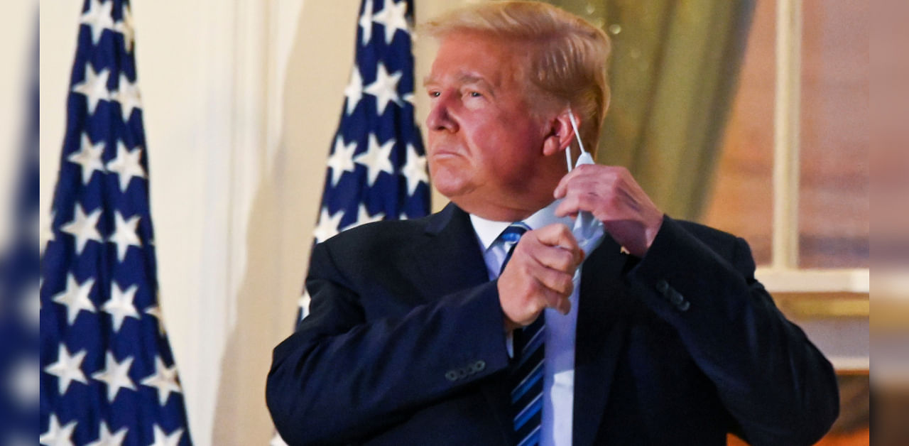 US President Donald Trump pulls off his protective face mask as he poses atop the Truman Balcony of the White House after returning from being hospitalized at Walter Reed Medical Center for coronavirus disease treatment, in Washington, US October 5, 2020. Credit: REUTERS Photo