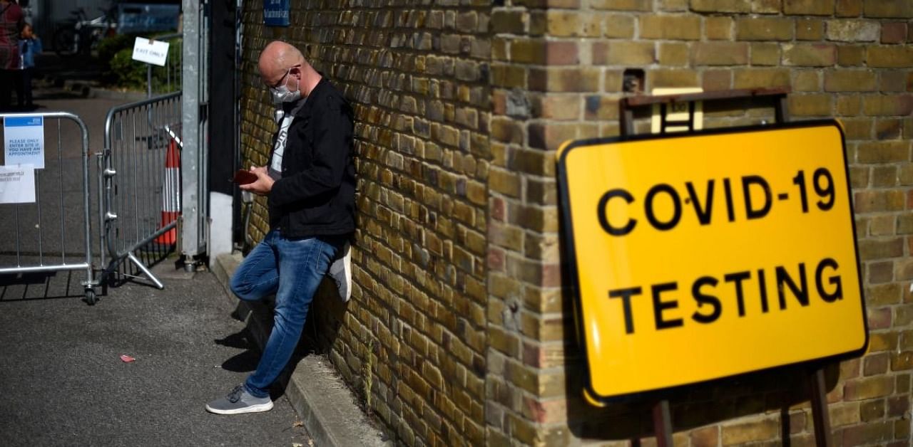 A man wearing a face covering due to the Covid-19 pandemic, queues to attend a novel coronavirus walk-in testing centre in East Ham in east London. Credit: AFP