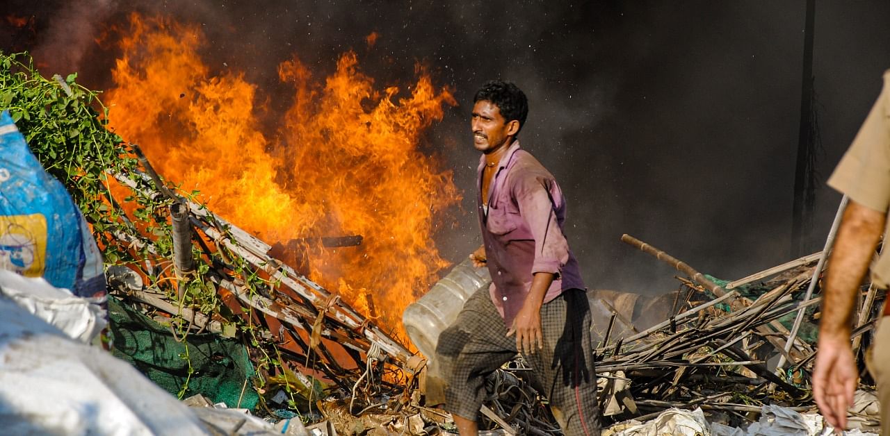 A local attempts to douse fire that broke out in a slum area, at Sihani in Ghaziabad. Credit: PTI Photo