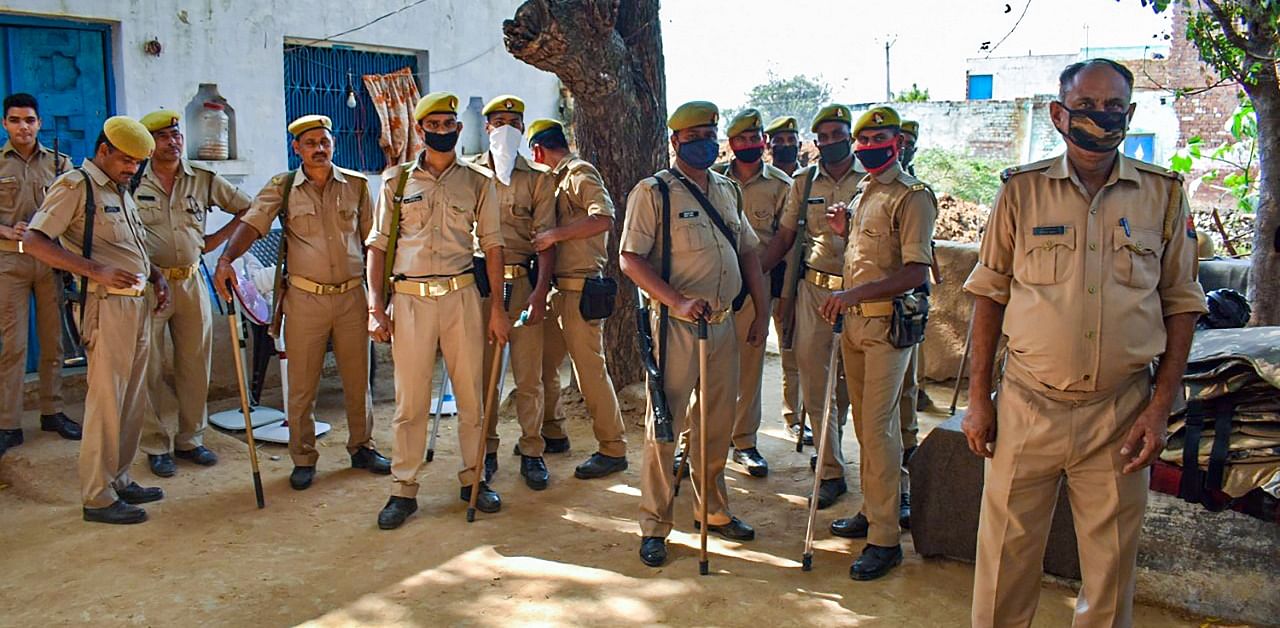 Police personnel stand guard outside the residence of a 19-year-old Dalit woman who died after being allegedly gang-raped, at Bulgadi village in Hathras. Credit: PTI Photo
