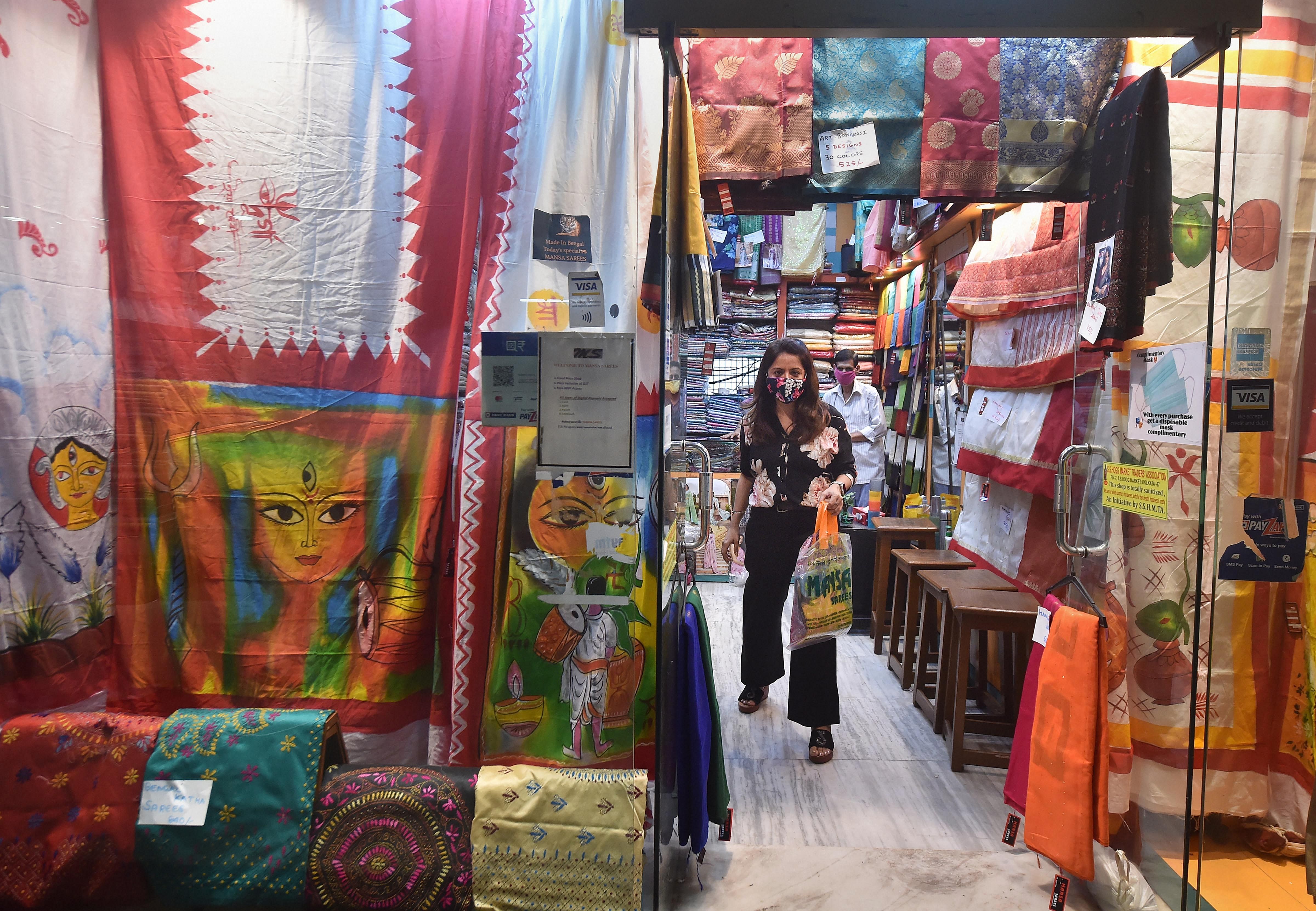 A customer comes out of a shop after shopping for upcoming Durga Puja festival in Kolkata, Tuesday, Sept 29, 2020. Credit: PTI Photo