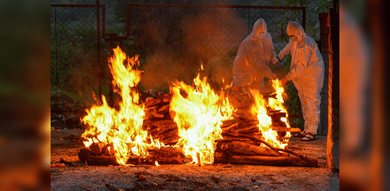 Relatives and health workers wearing PPE kits cremate the bodies of persons who died of Covid-19, at a crematorium in Karad, Monday, Oct. 5, 2020. Credit: PTI Photo