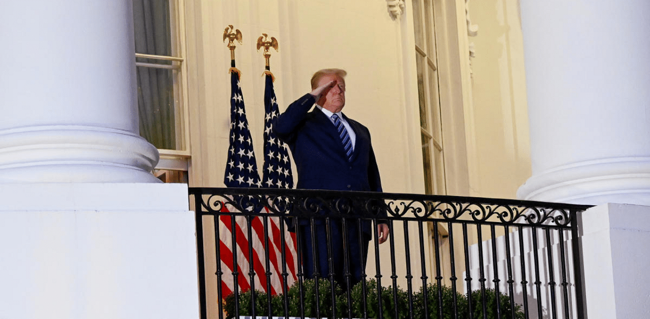 US President Donald Trump salutes as he poses without a face mask on the Truman Balcony of the White House after returning from being hospitalized at Walter Reed Medical Center for Covid-19 treatment. Credit: Reuters Photo 