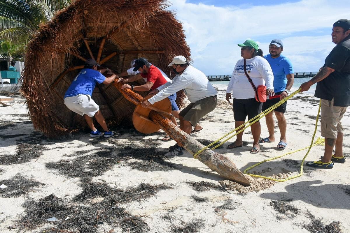 Workers remove a sunshide in preparation for the arrival of Hurrican Delta, in Puerto Morelos, Quintana Roo state, Mexico. Credit: AFP