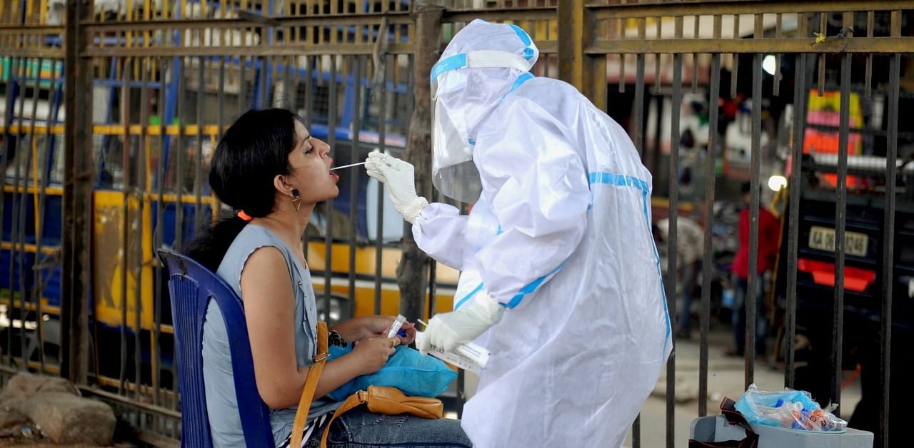 A health worker collects a sample from a woman for the Covid-19 Rapid Antigen Test, at a city market in Bengaluru. Credit: PTI Photo