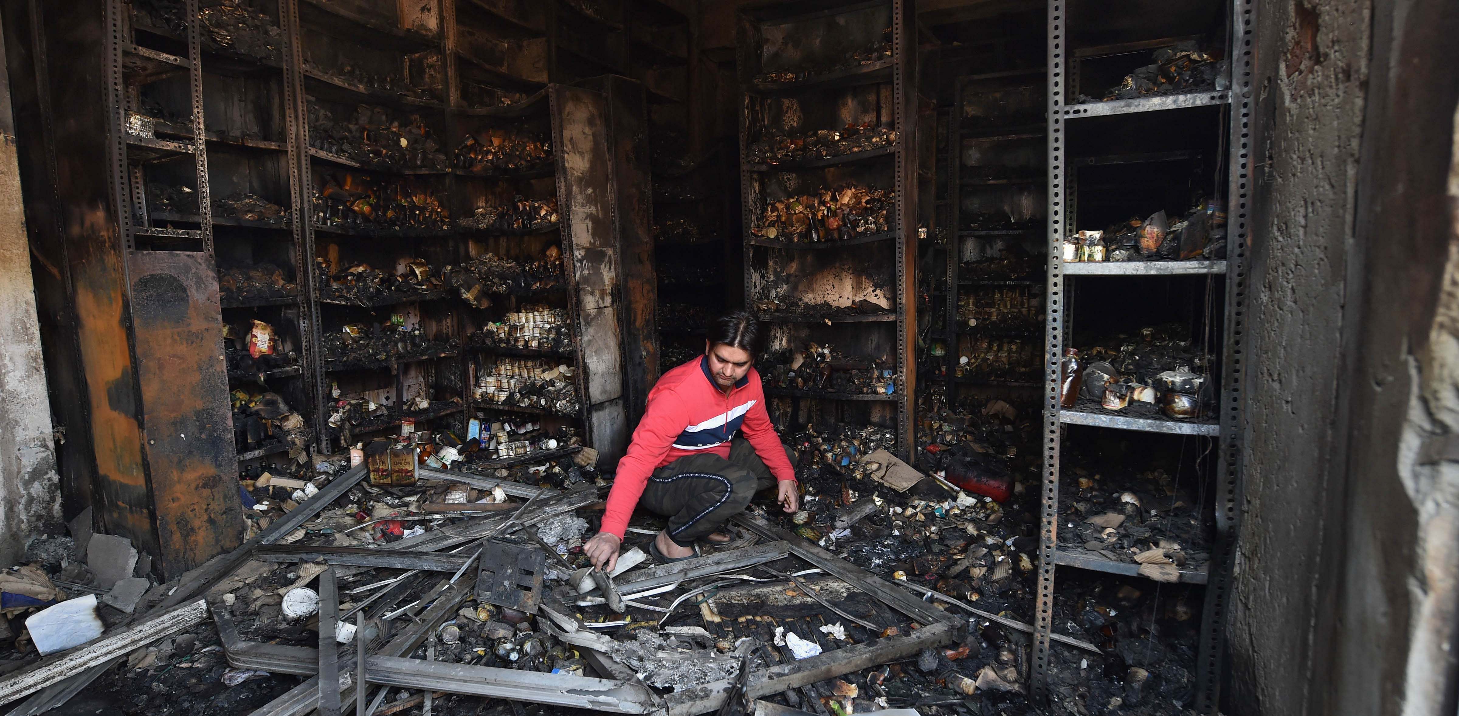  A shopkeeper sorts through the charred remains of a vandalized and burned shop, following Tuesday's violence, at Khajuri Khas extension area of northeast Delhi. Credit: PTI File Photo