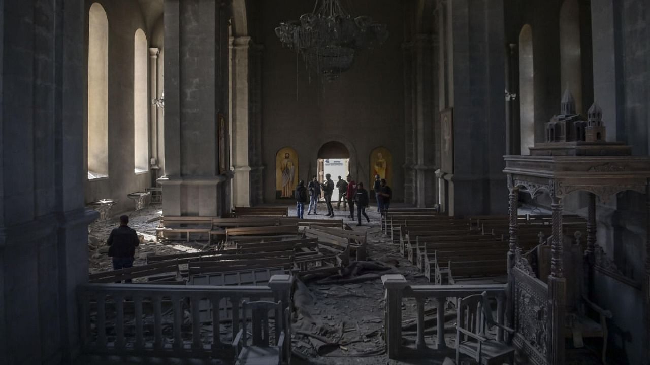 Journalists and local inhabitants stand on October 8, 2020 inside the damaged Ghazanchetsots (Holy Saviour) Cathedral in the historic city of Shusha, some 15 kilometers from the disputed Nagorno-Karabakh province's capital Stepanakert, that was hit by a bomb as fighting between Armenian and Azerbaijani forces spilled over. Credit: AFP.