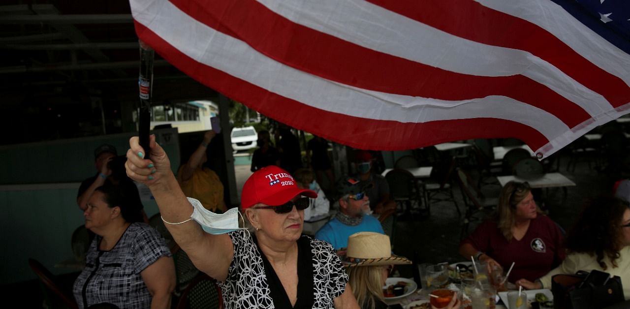 A supporter of U.S. President Donald Trump waves an American flag during a boat parade to rally for his reelection. Credit: Reuters Photo