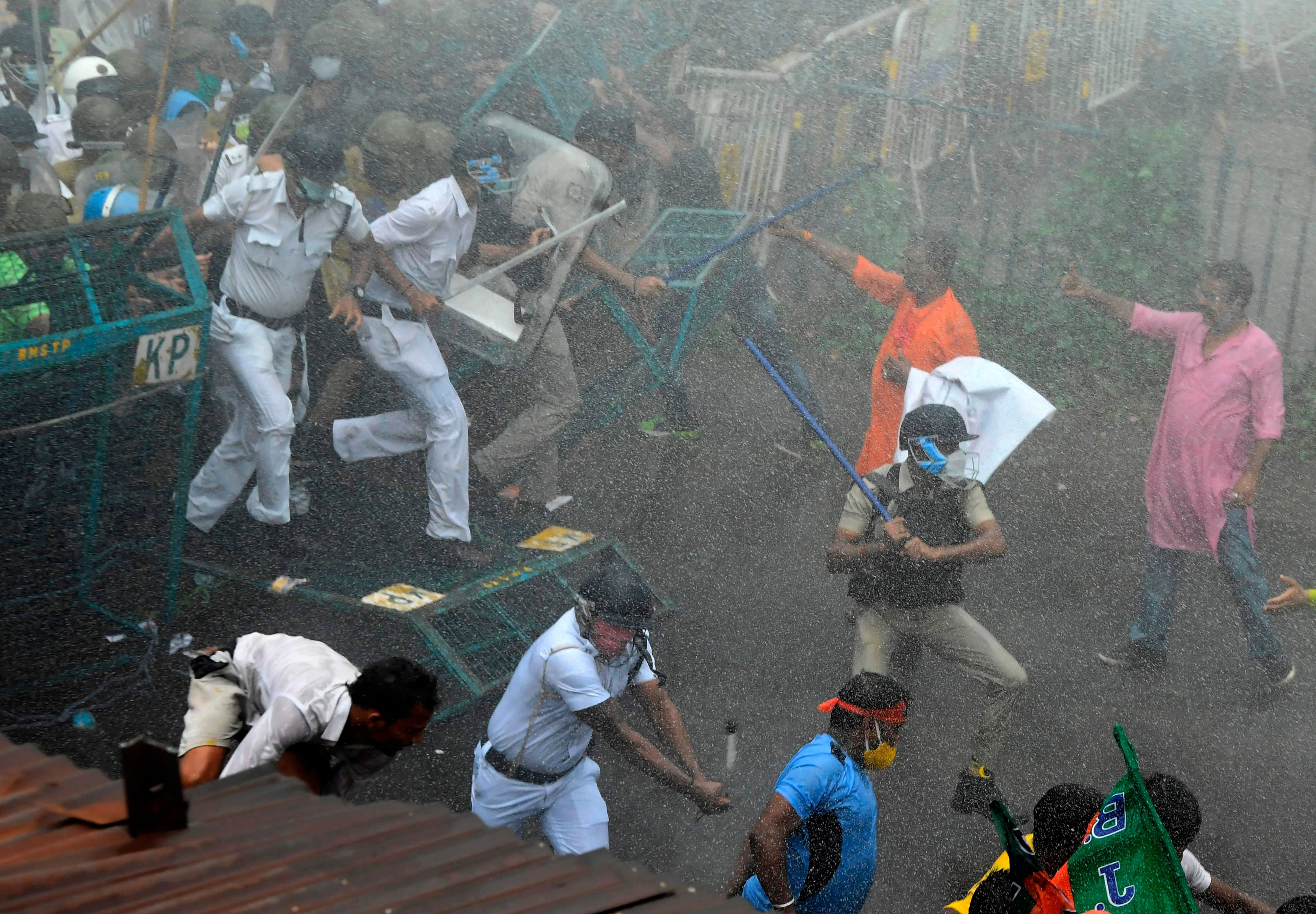 Police charge towards Bhartiya Janata Party (BJP) activists through a police barricade during a protest march towards West Bengal Chief Minister Mamata Banerjee's office to protest against the "worsening" law and order situation in the state, in Kolkata on October 8, 2020. Credit: AFP